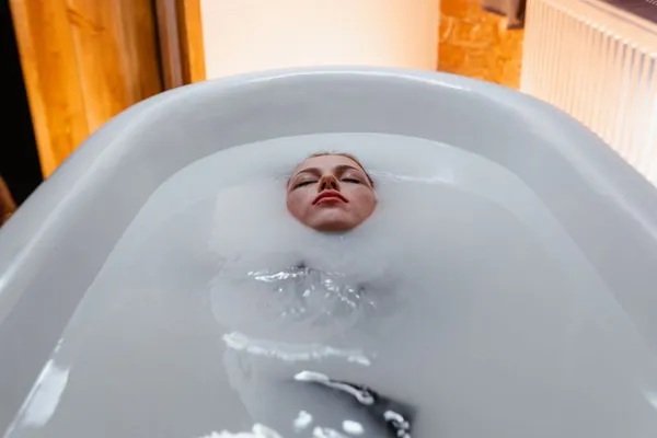 Person floating in a milky cold plunge tub at a studio