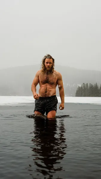 Man standing waist-deep in an icy lake