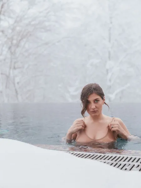 Woman in a snow-surrounded outdoor plunge pool
